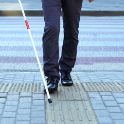 一个使用盲杖的视障人士的图像，表示BCD是一种致盲疾病。